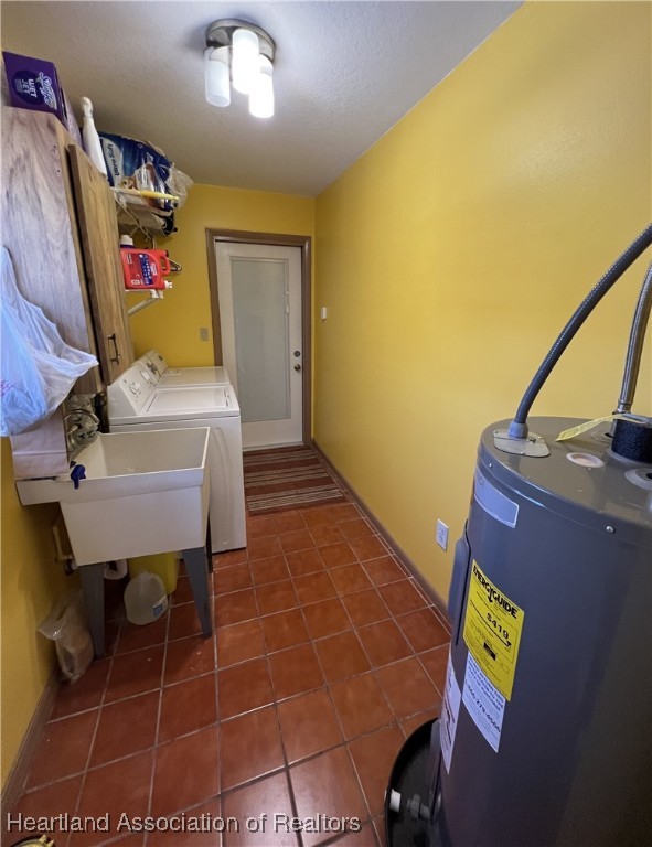 laundry room with washer and clothes dryer, laundry area, water heater, and dark tile patterned floors