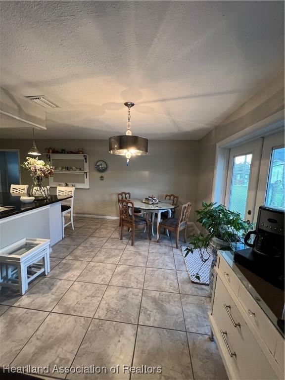 dining space featuring a textured ceiling, light tile patterned floors, and visible vents