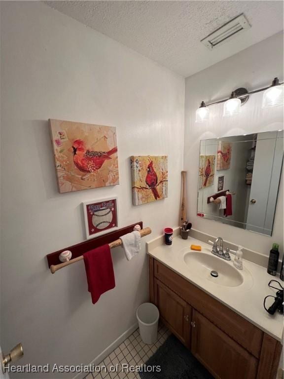 bathroom featuring a textured ceiling, vanity, visible vents, and tile patterned floors