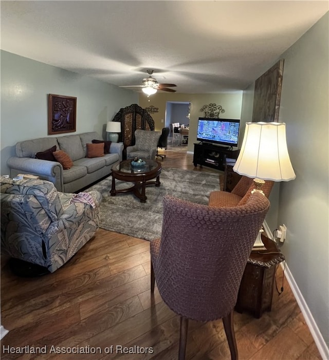 living room with ceiling fan, baseboards, and wood finished floors