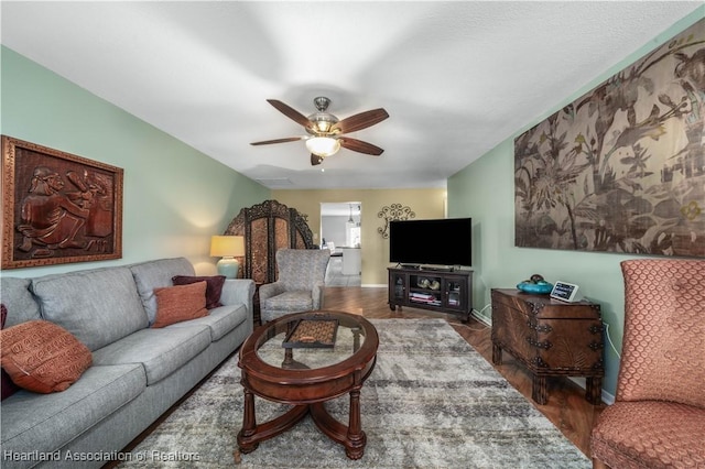 living area with baseboards, wood finished floors, and a ceiling fan