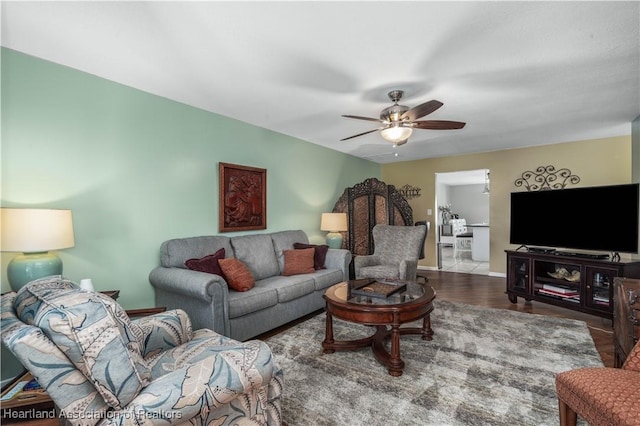 living area featuring baseboards, ceiling fan, and wood finished floors