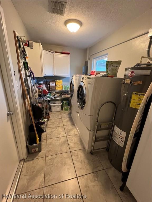 laundry area with light tile patterned floors, cabinet space, visible vents, washing machine and dryer, and electric water heater