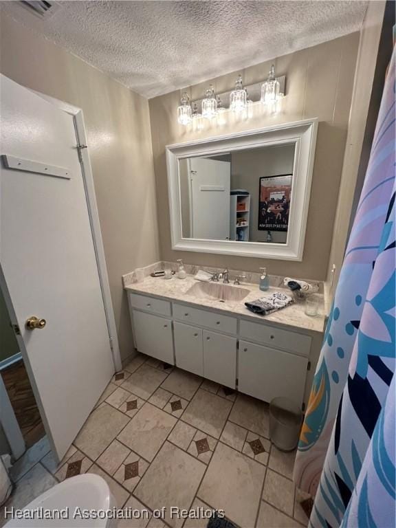 full bath featuring visible vents, vanity, and a textured ceiling