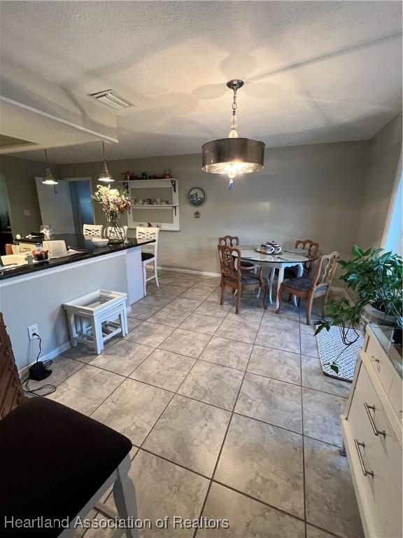 dining room featuring light tile patterned floors, baseboards, visible vents, and a textured ceiling