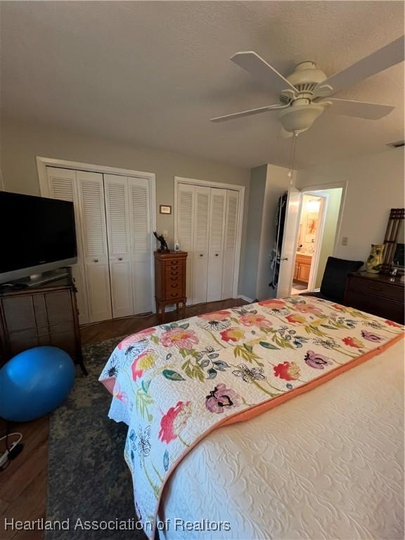 bedroom featuring ceiling fan, dark wood-style flooring, and multiple closets