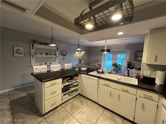 kitchen with a raised ceiling, dishwasher, a peninsula, pendant lighting, and a sink