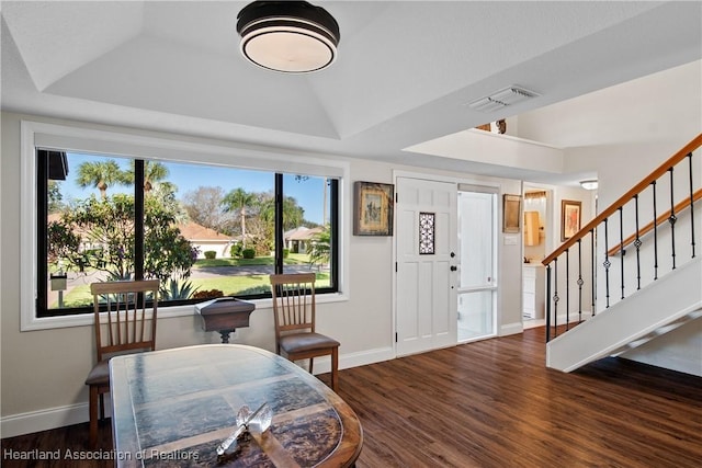 foyer with stairs, a tray ceiling, baseboards, and wood finished floors