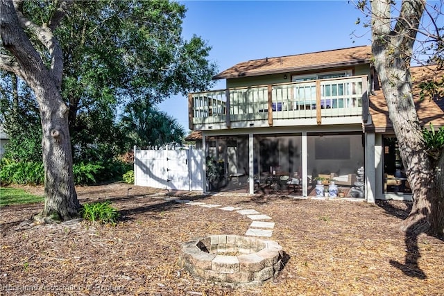 rear view of property featuring an outdoor fire pit and a balcony