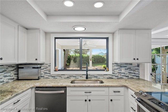 kitchen with a tray ceiling, tasteful backsplash, a sink, white cabinets, and stainless steel appliances