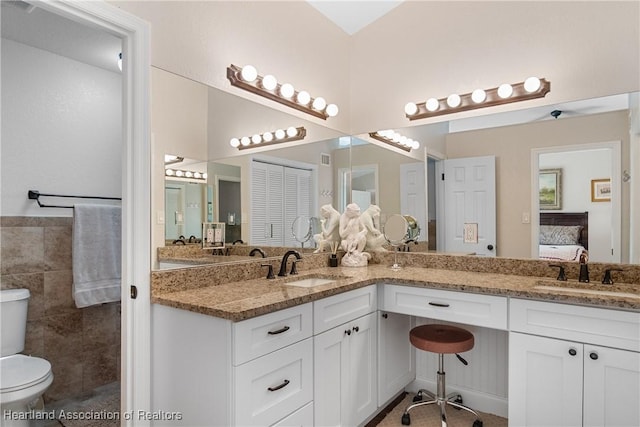 ensuite bathroom with double vanity, a sink, ensuite bath, and toilet