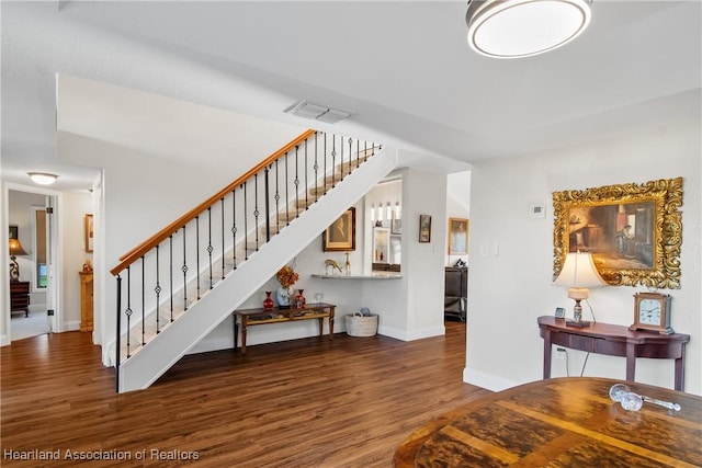 interior space featuring visible vents, baseboards, wood finished floors, and stairway
