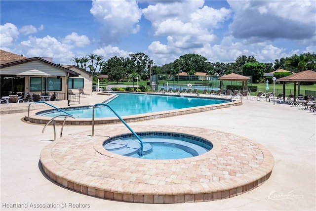 pool featuring a hot tub, a patio, a gazebo, and fence