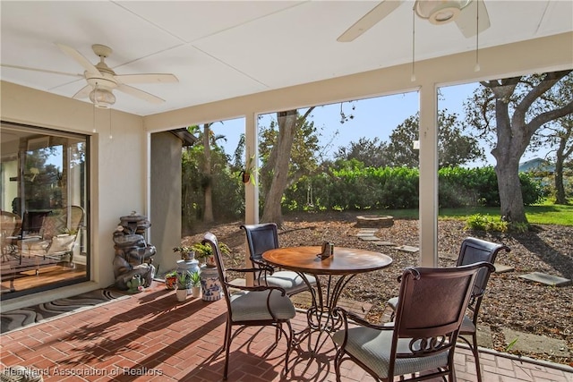 sunroom with ceiling fan and brick floor