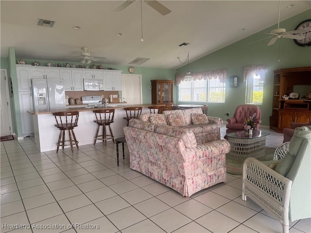 living room with light tile patterned floors, visible vents, and vaulted ceiling