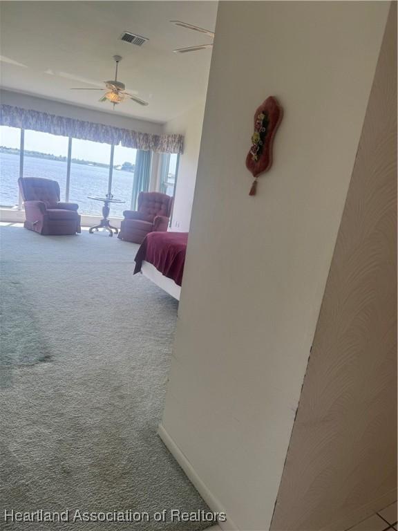 carpeted bedroom with visible vents, baseboards, and a ceiling fan