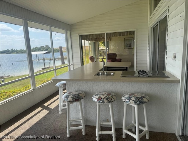 sunroom featuring vaulted ceiling, a water view, and a sink