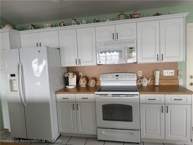 kitchen with white appliances, light tile patterned floors, white cabinetry, dark countertops, and backsplash