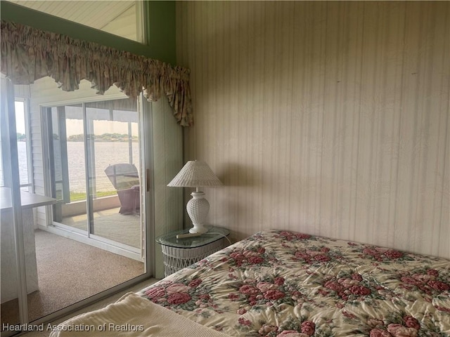 bedroom featuring a water view, access to exterior, and carpet flooring