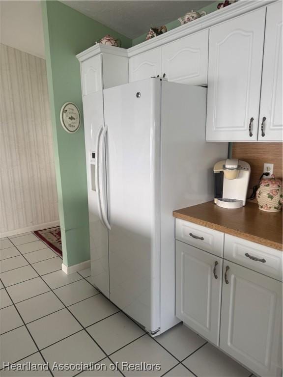 kitchen with white cabinets, light tile patterned floors, and white fridge with ice dispenser