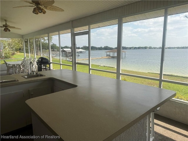 sunroom featuring a wealth of natural light, a sink, and a water view