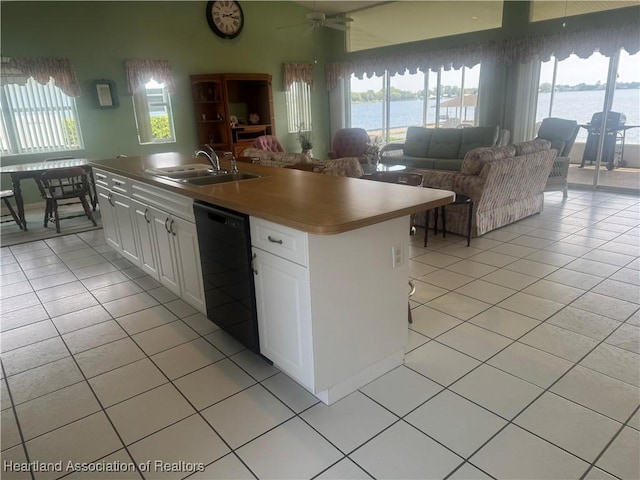 kitchen with black dishwasher, open floor plan, light tile patterned floors, and a sink