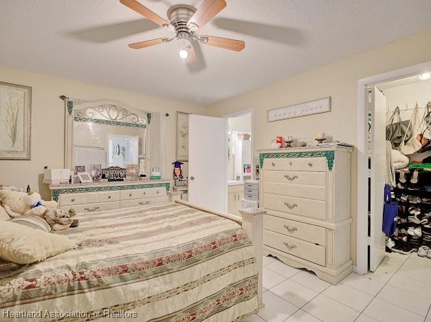 bedroom featuring a textured ceiling, ensuite bath, ceiling fan, and light tile patterned flooring