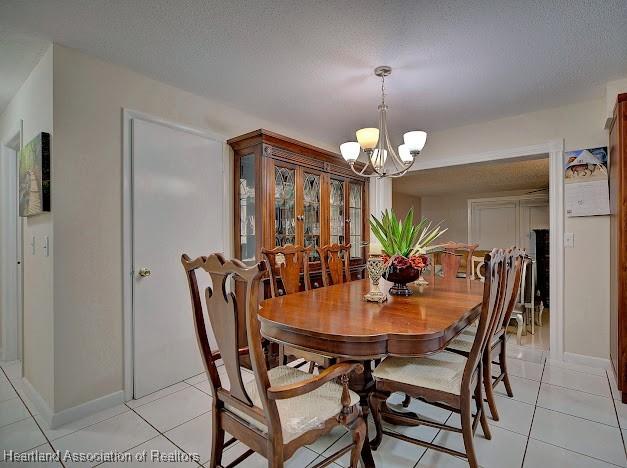 tiled dining space featuring a textured ceiling and an inviting chandelier