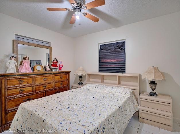 bedroom with a textured ceiling, ceiling fan, and light tile patterned flooring