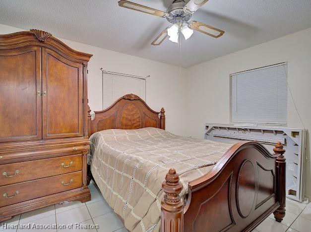 bedroom with ceiling fan, light tile patterned flooring, and a textured ceiling