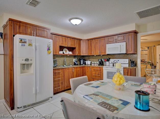 kitchen with sink, a textured ceiling, white appliances, decorative backsplash, and light tile patterned flooring