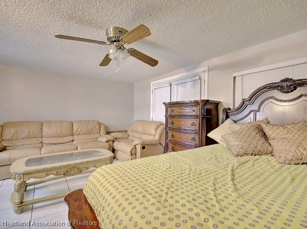 bedroom with ceiling fan, light tile patterned floors, and a textured ceiling