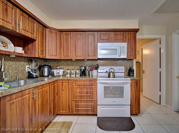 kitchen with white appliances, sink, light tile patterned floors, and tasteful backsplash