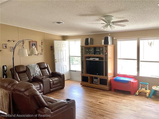 living room with ceiling fan, light hardwood / wood-style floors, and a textured ceiling