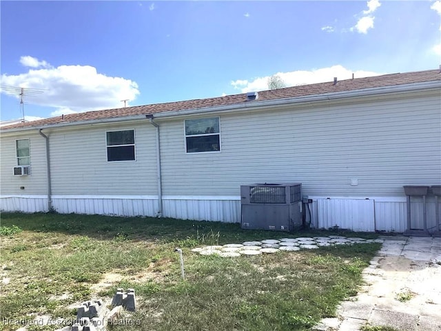 view of side of property with cooling unit, a yard, and central AC