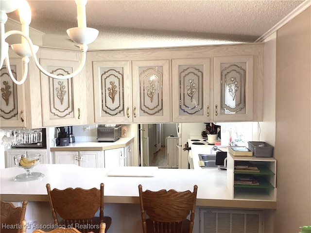 kitchen featuring cream cabinetry, a textured ceiling, hanging light fixtures, and a breakfast bar