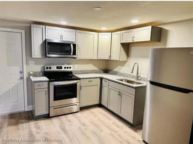 kitchen featuring gray cabinetry, sink, stainless steel appliances, and light hardwood / wood-style floors