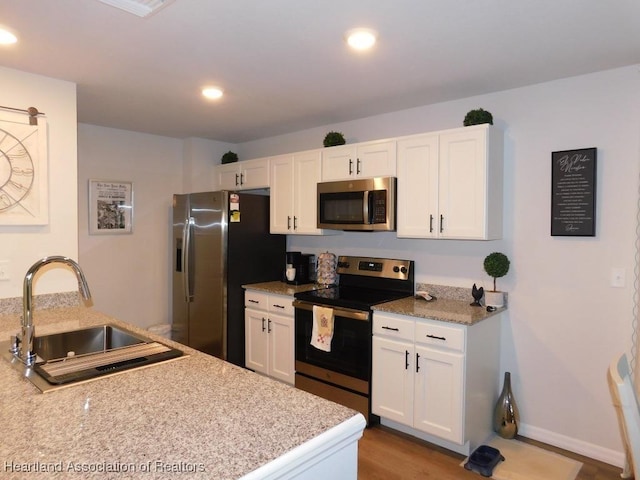 kitchen with light stone counters, sink, white cabinets, and appliances with stainless steel finishes