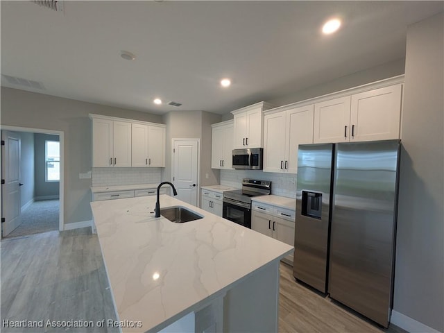 kitchen with white cabinets, an island with sink, appliances with stainless steel finishes, and sink