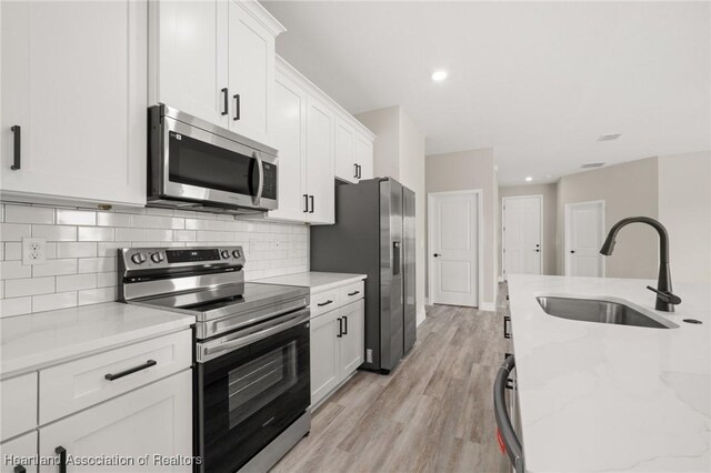4924 San Lorenzo Dr, Sebring, FL 33872 - kitchen featuring stainless steel appliances, white cabinets, a sink, and backsplash