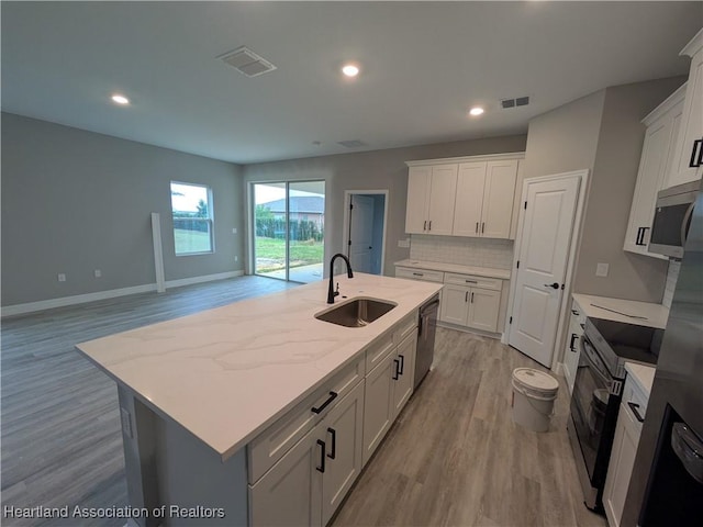 kitchen with sink, white cabinetry, a kitchen island with sink, and dishwasher