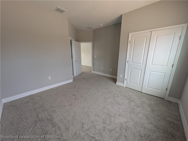 unfurnished bedroom with light carpet and a closet