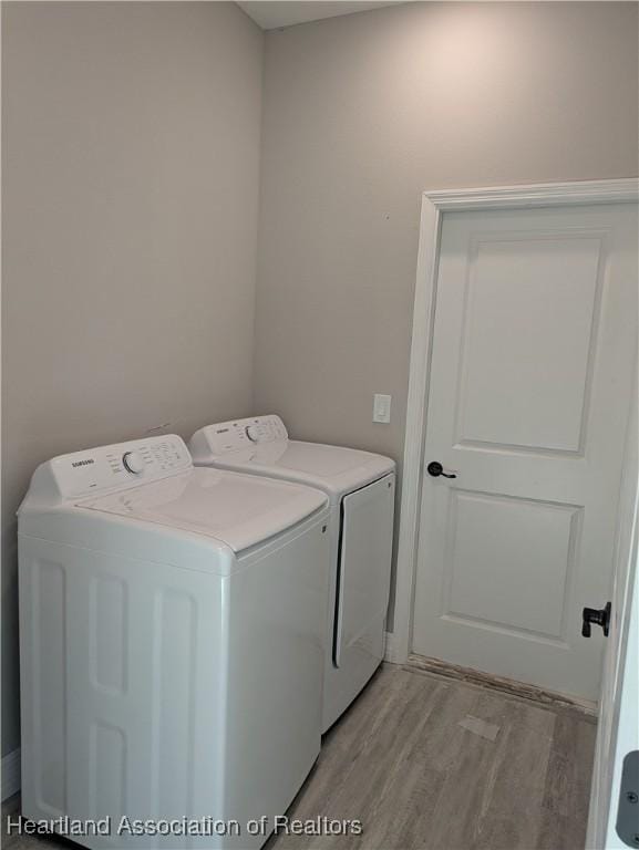 clothes washing area with light wood-type flooring and washer and clothes dryer