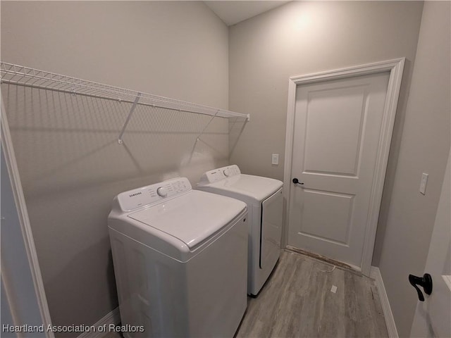 clothes washing area with light wood-type flooring and washer and clothes dryer