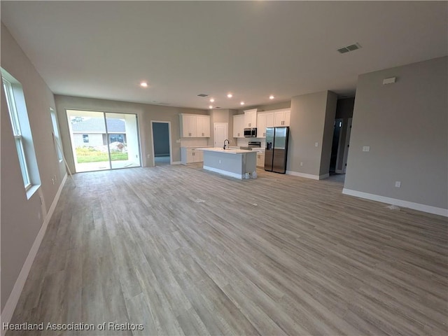 unfurnished living room featuring light wood-type flooring and sink