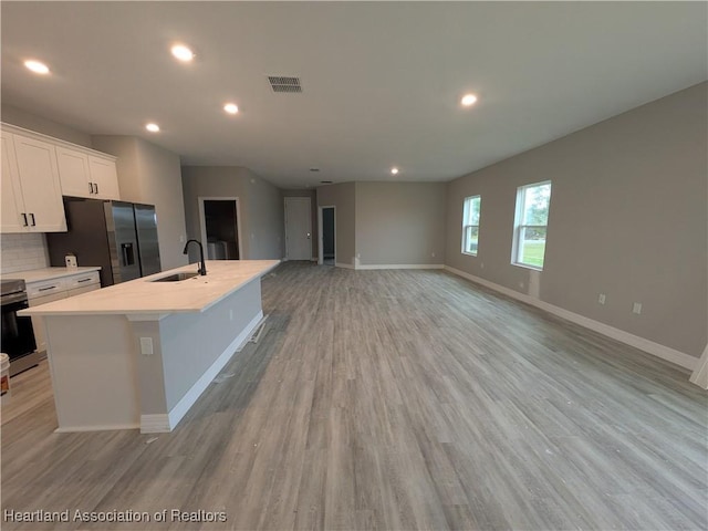 kitchen with appliances with stainless steel finishes, an island with sink, white cabinets, decorative backsplash, and sink