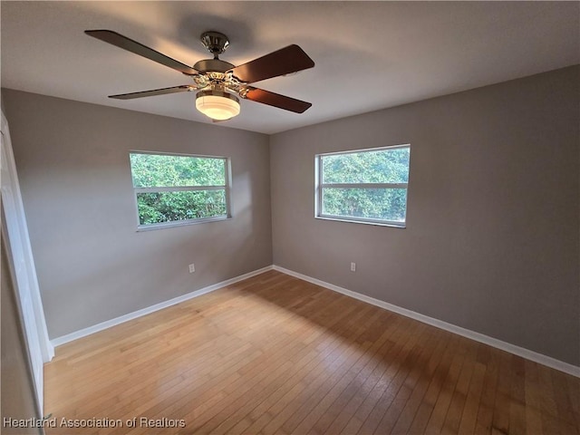 spare room featuring ceiling fan, light hardwood / wood-style flooring, and a healthy amount of sunlight