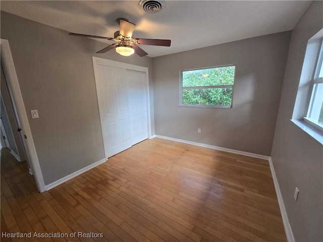 unfurnished bedroom with ceiling fan, a closet, and light wood-type flooring