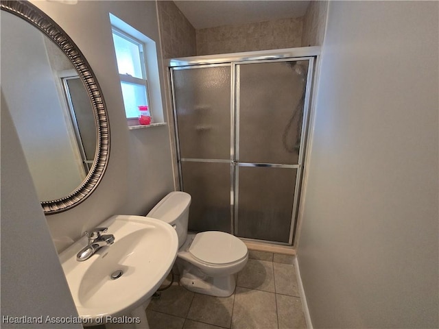 bathroom with tile patterned floors, toilet, a shower with shower door, and sink