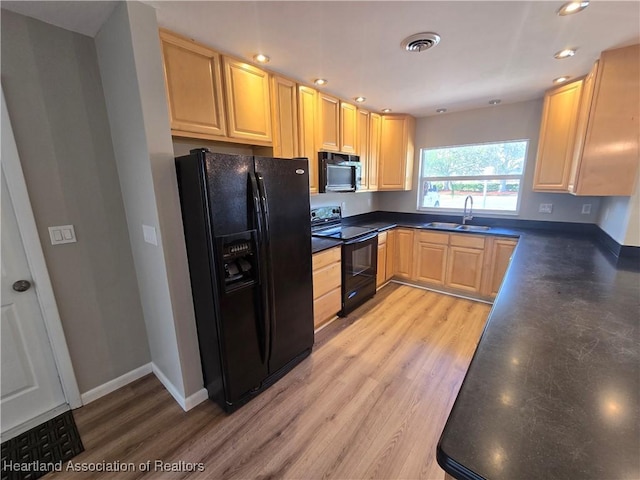 kitchen with light wood-type flooring, light brown cabinets, sink, and black appliances